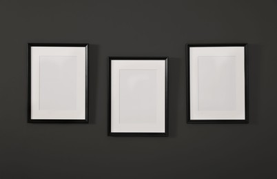 Photo of Empty frames on black wall. Mockup for design