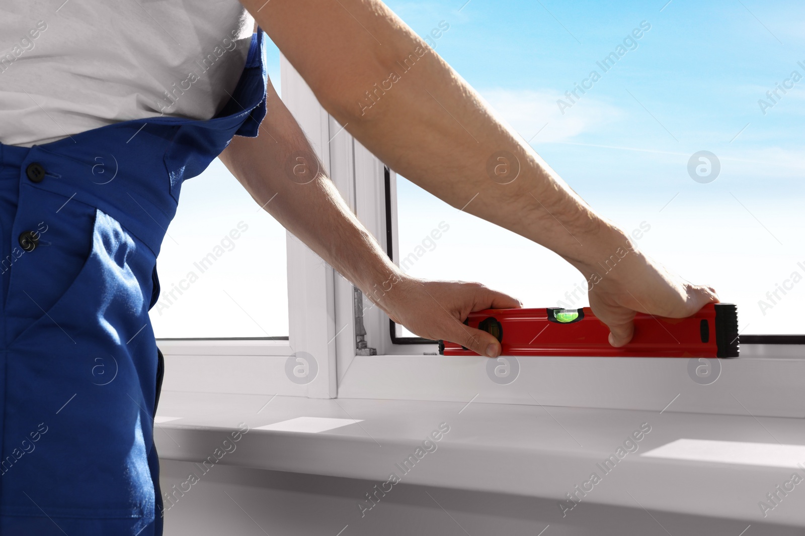 Photo of Worker using bubble level after plastic window installation indoors, closeup