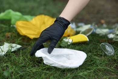Photo of Woman collecting garbage on green grass, closeup