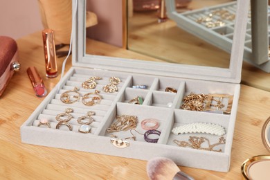 Photo of Elegant jewelry box with beautiful bijouterie and makeup products on wooden table