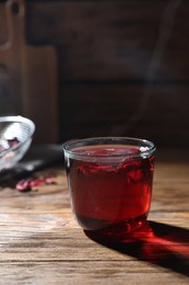 Delicious hibiscus tea in glass on wooden table. Space for text