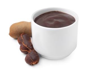 Photo of Bowl of tamarind sauce and fresh pods isolated on white