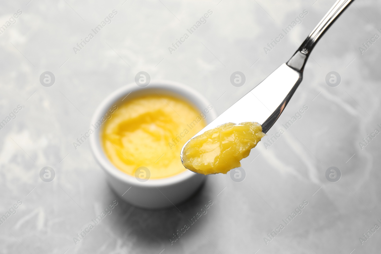 Photo of Knife with clarified butter over grey table