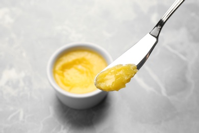 Knife with clarified butter over grey table