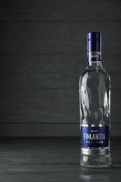 Photo of MYKOLAIV, UKRAINE - OCTOBER 03, 2019: Bottle of Finlandia vodka on wooden table against grey background. Space for text