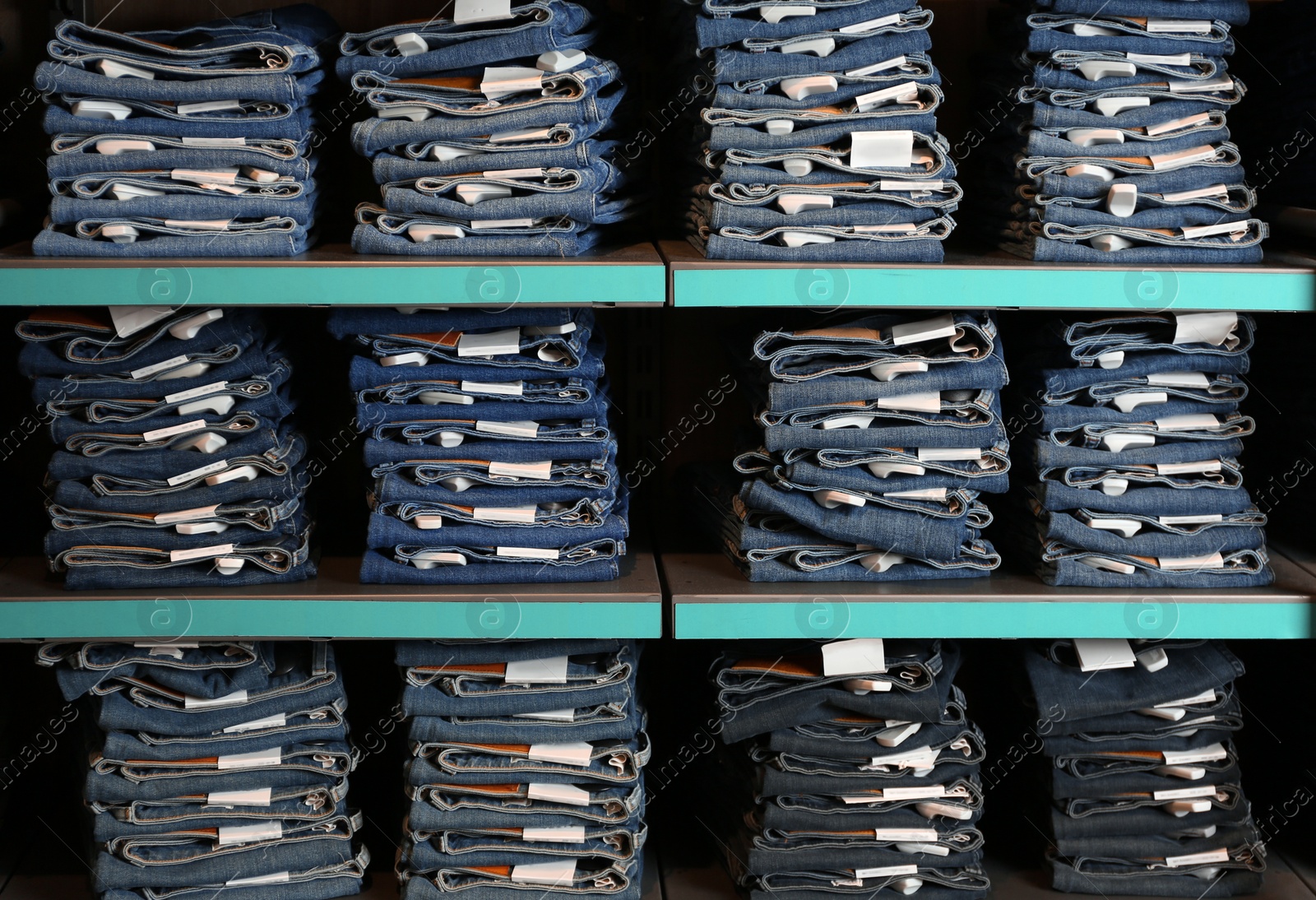 Photo of Collection of stylish jeans on shelves in shop