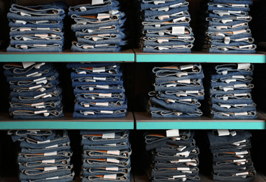 Photo of Collection of stylish jeans on shelves in shop