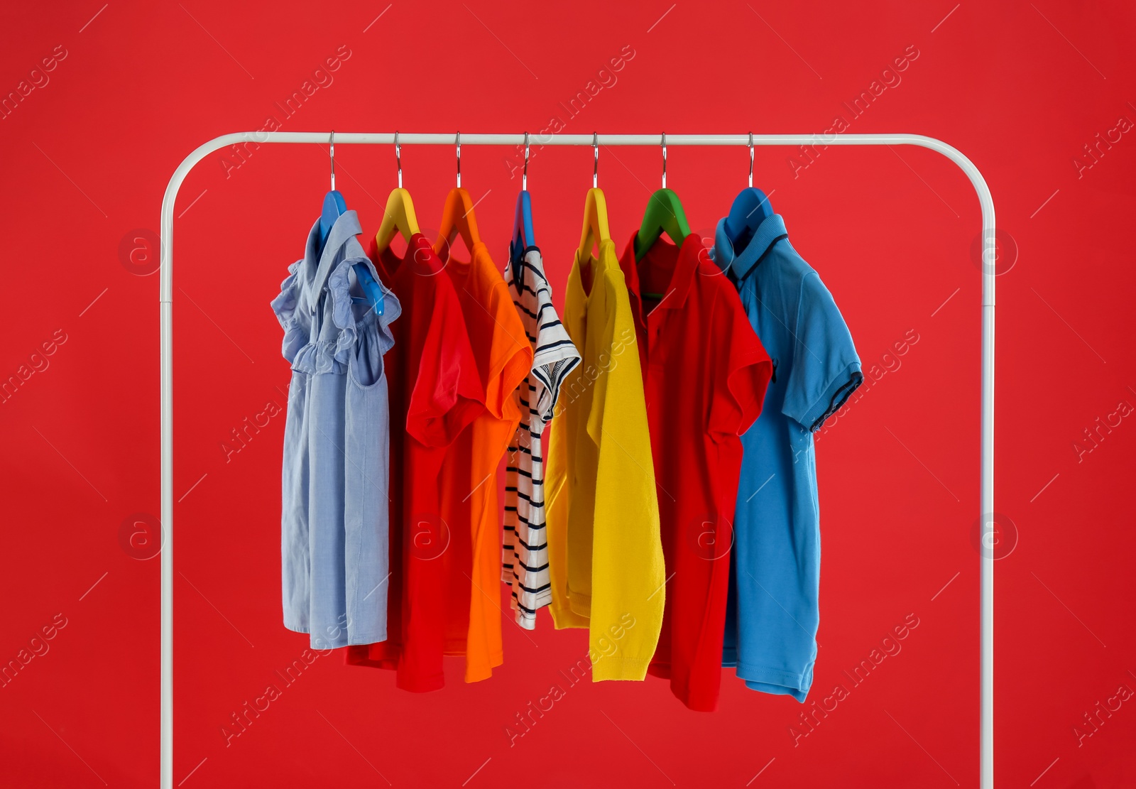 Photo of Rack with stylish children clothes on red background