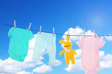 Image of Baby clothes and crochet toy drying on washing line against sky