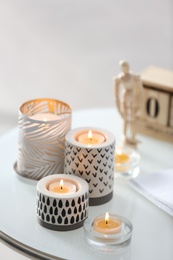 Photo of Burning candles in holders on white table indoors