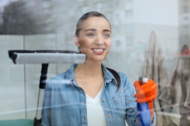 Young woman cleaning window glass at home