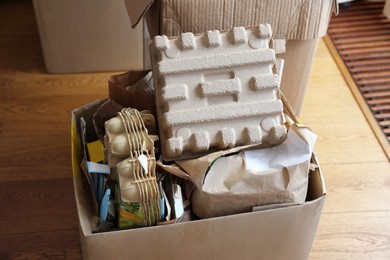 Photo of Reuse concept. Different trash in cardboard boxes for recycling indoors