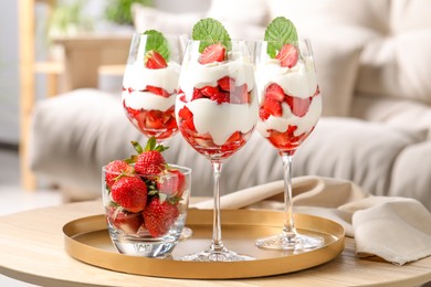 Photo of Delicious strawberries with whipped cream on wooden table indoors