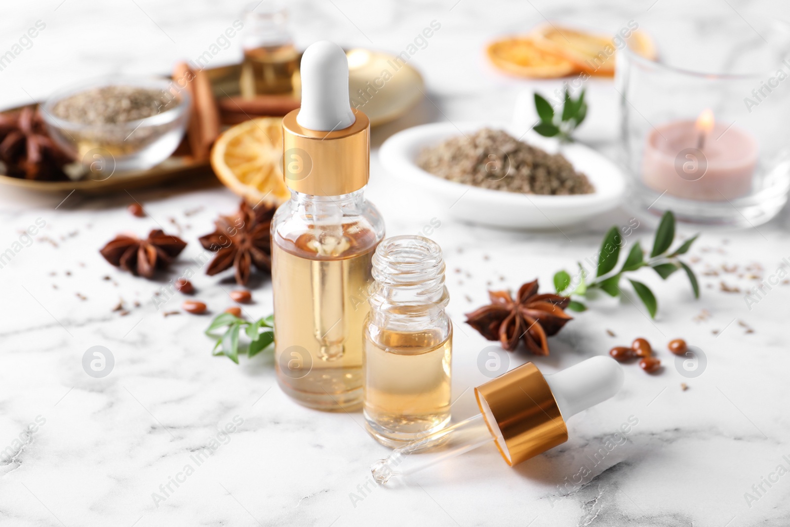 Photo of Anise essential oil and spice on white marble table