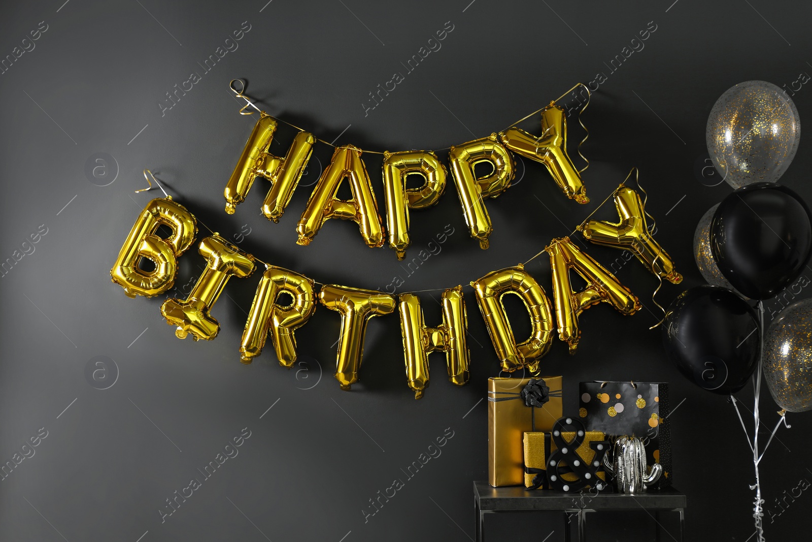 Photo of Room interior with gift boxes and phrase HAPPY BIRTHDAY made of golden balloon letters