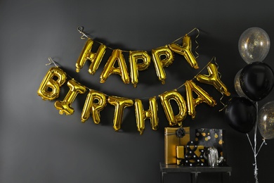 Photo of Room interior with gift boxes and phrase HAPPY BIRTHDAY made of golden balloon letters