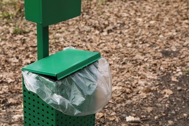 Photo of Trash bin with plastic bag in park. Space for text