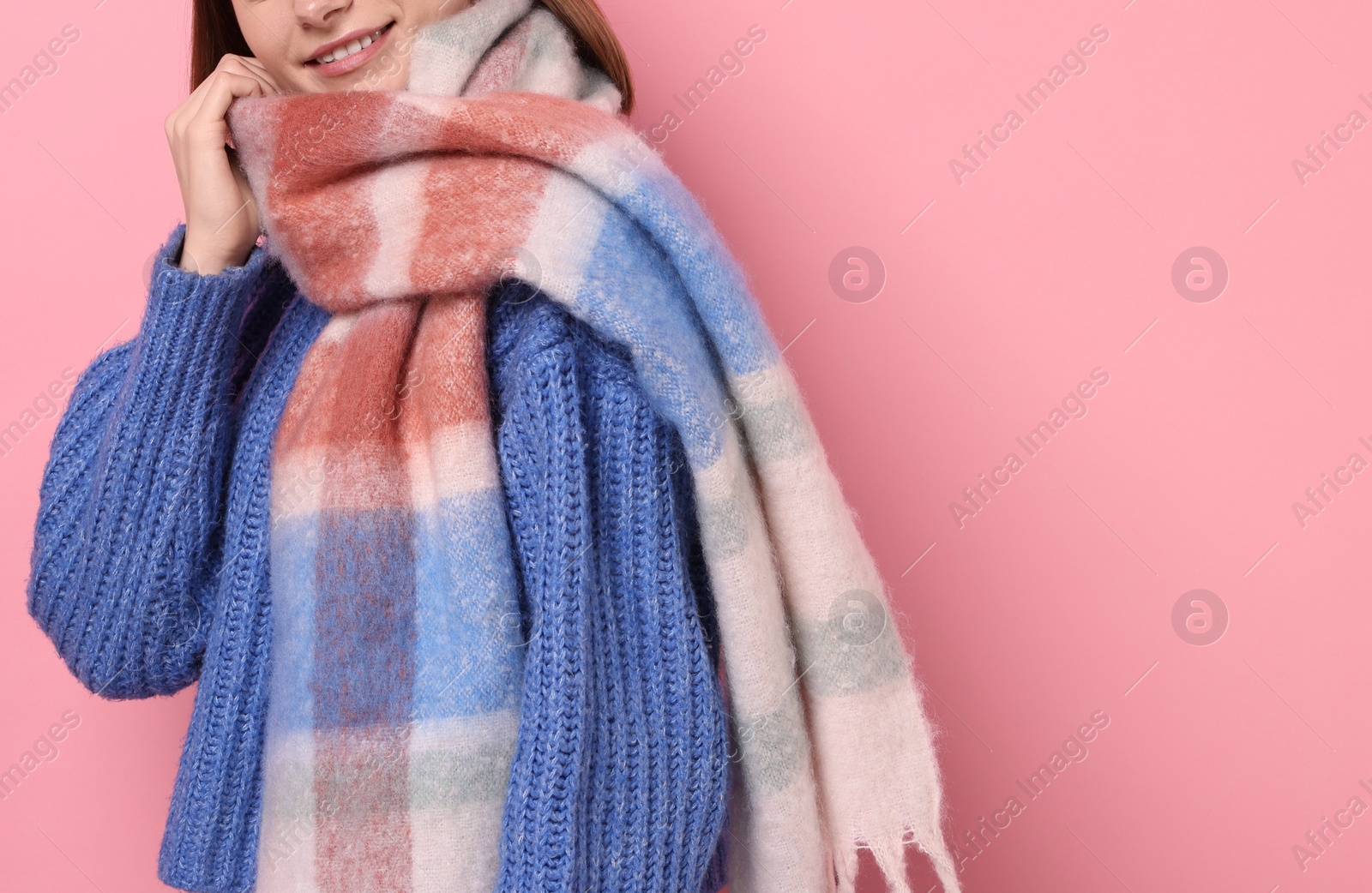 Photo of Woman in warm scarf on pink background, closeup. Space for text