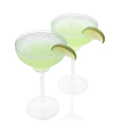 Delicious Margarita cocktail with ice cubes in glasses, salt and lime isolated on white