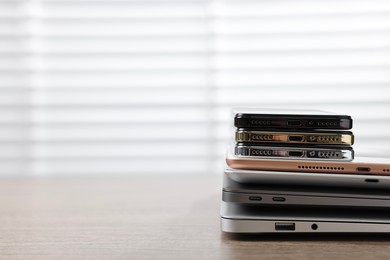 Many different modern gadgets on wooden table indoors. Space for text