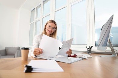 Photo of Happy woman working with documents at wooden table in office
