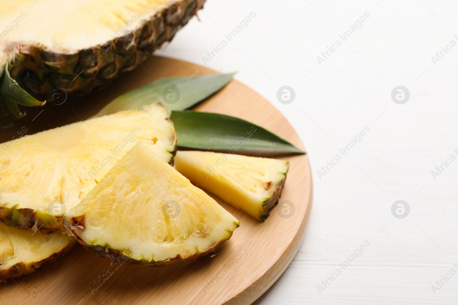 Photo of Slices of ripe juicy pineapple on white wooden table, closeup. Space for text