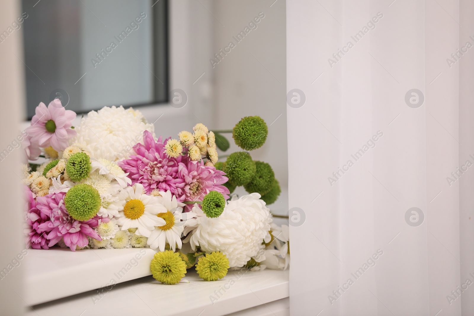 Photo of Bouquet of beautiful chrysanthemum flowers on window sill indoors, space for text