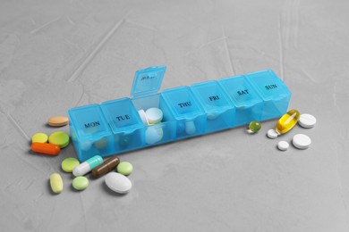 Weekly pill box with medicaments on grey table
