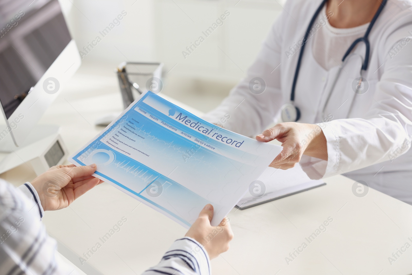 Photo of Doctor showing medical record to patient at desk in clinic, closeup