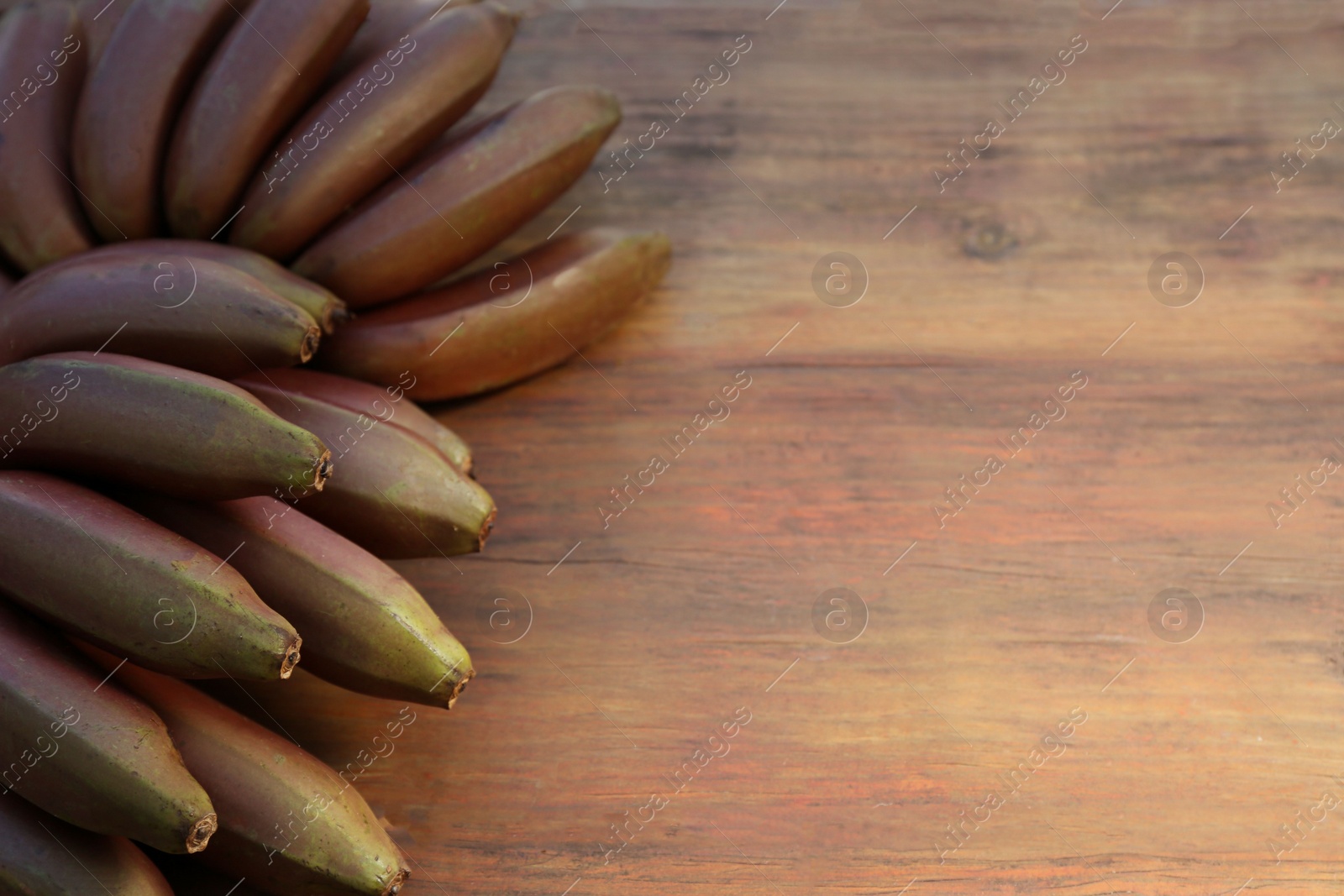 Photo of Tasty purple bananas on wooden table, above view. Space for text