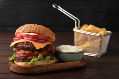 Photo of Tasty cheeseburger with patties, tomato and sauce on wooden table