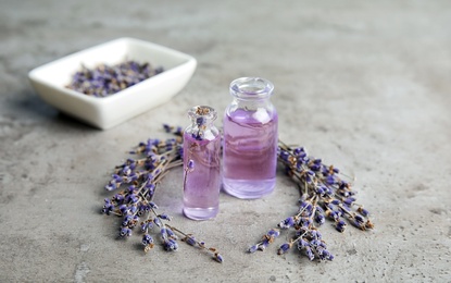 Natural herbal oil in glass bottles and lavender flowers on color background