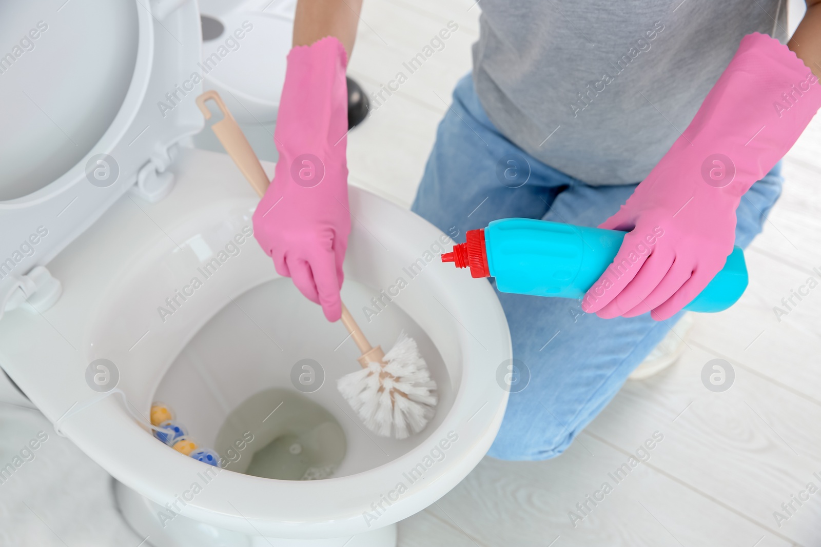 Photo of Woman cleaning toilet bowl in bathroom