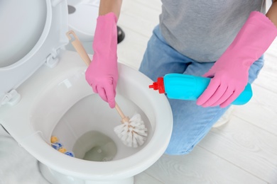 Woman cleaning toilet bowl in bathroom