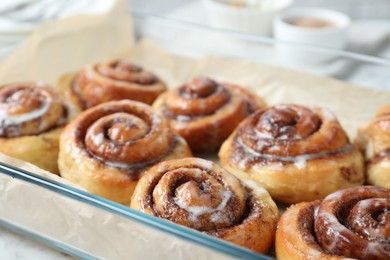 Photo of Baking dish with tasty cinnamon rolls on white table, closeup