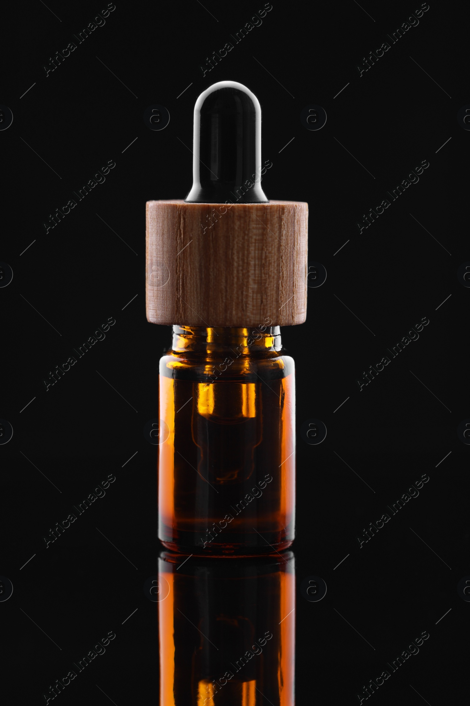 Photo of Tincture in bottle on mirror table against dark background