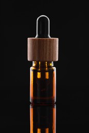 Photo of Tincture in bottle on mirror table against dark background