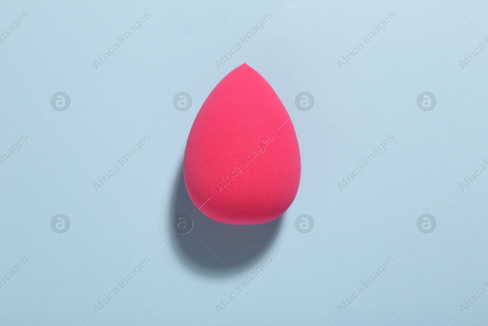 Photo of Pink makeup sponge on light blue background, top view