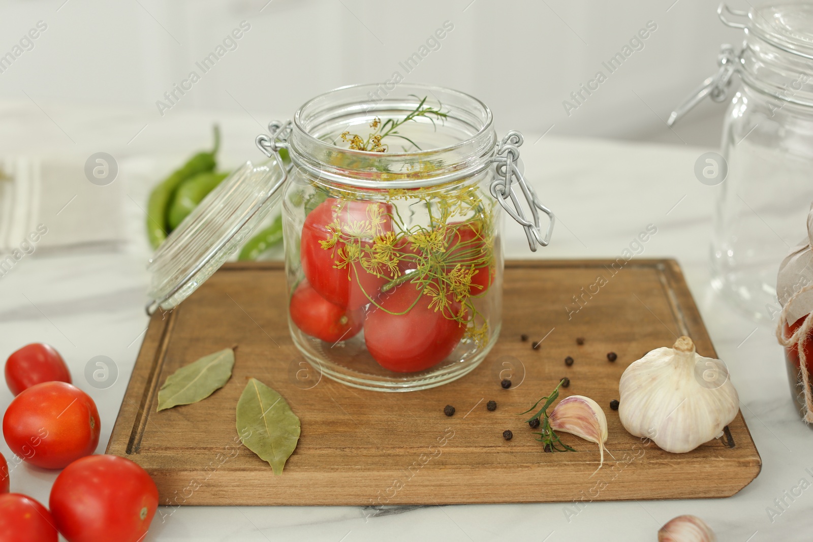 Photo of Tomatoes and dill in pickling jar on kitchen table