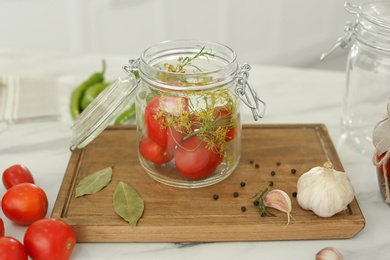 Photo of Tomatoes and dill in pickling jar on kitchen table