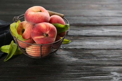 Photo of Fresh ripe donut peaches on black wooden table. Space for text