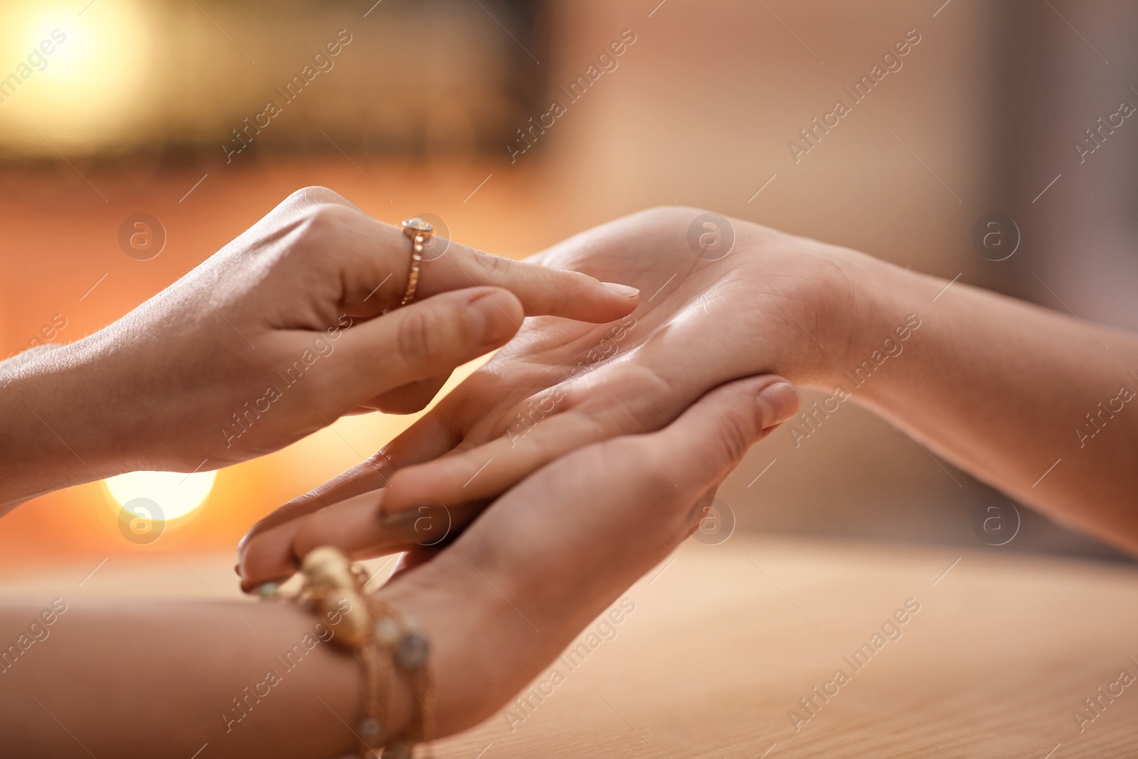 Photo of Chiromancer reading lines on woman's palm at table, closeup