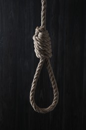 Photo of Tied rope noose against dark wooden background