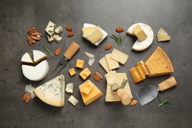 Flat lay composition with different sorts of cheese and knives on grey table
