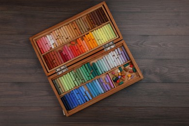 Photo of Drawing pastel set in box on wooden background, top view