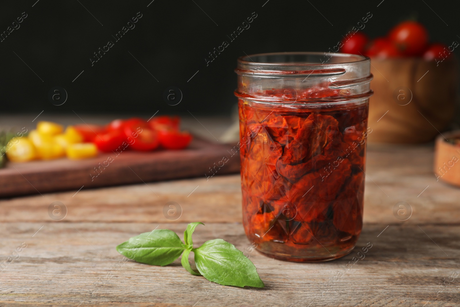 Photo of Jar with sun dried tomatoes on wooden table. Space for text