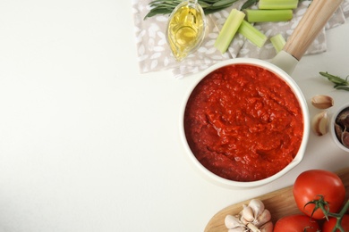 Photo of Flat lay composition with delicious tomato sauce in pan on white table. Space for text