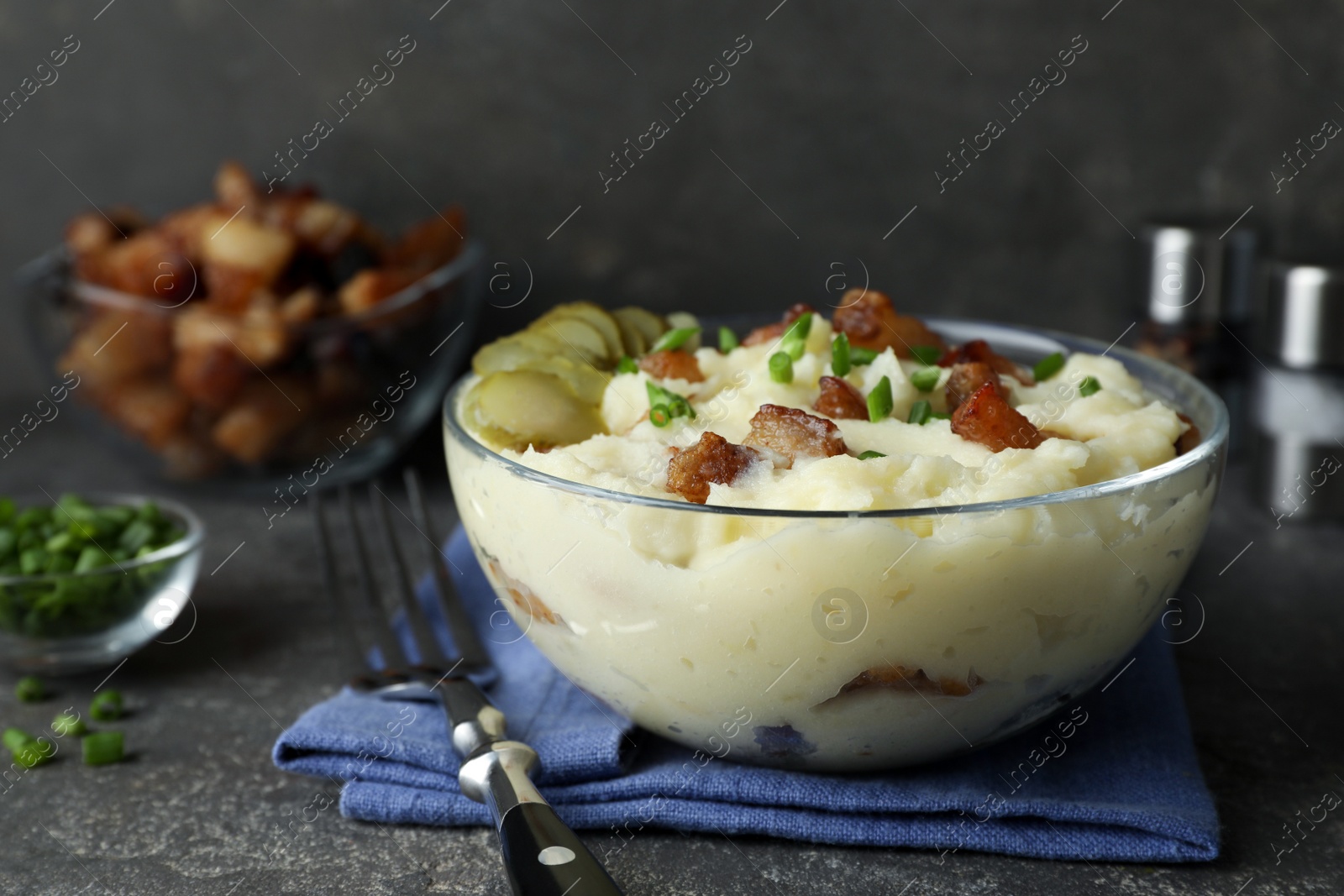 Photo of Potato puree and tasty fried cracklings on grey table. Cooked pork lard