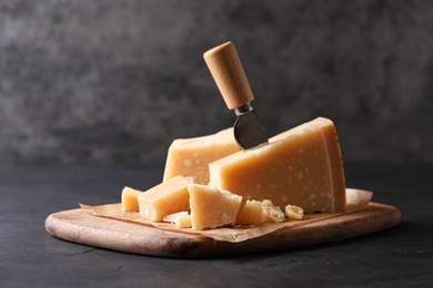 Photo of Delicious parmesan cheese with knife on black table