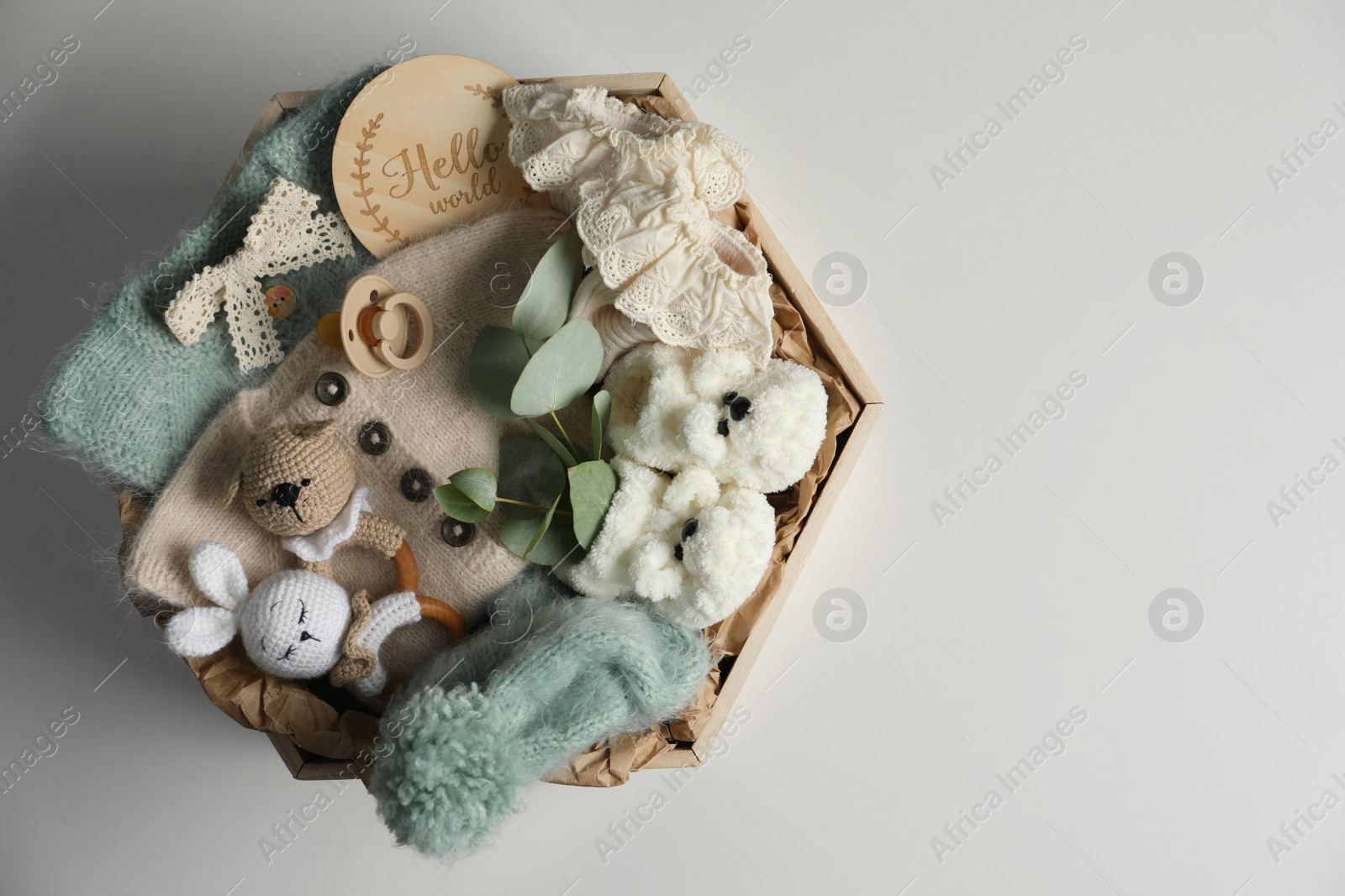 Photo of Box with baby clothes, shoes and accessories on light background, top view. Space for text